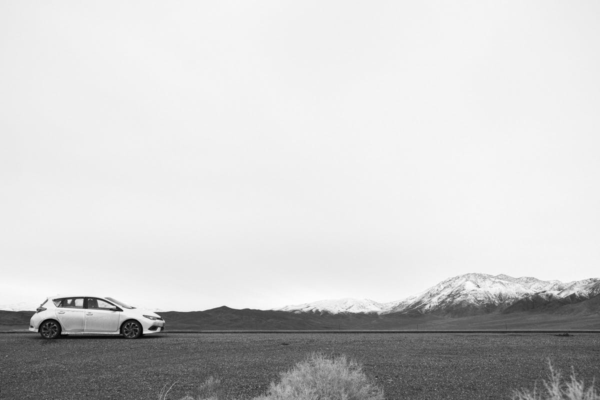A four-door white hatchback car in the Nevada desert. Photo by Joseph Dubon